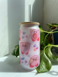 a pink and white cup with an animal design on it sitting next to a potted plant