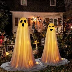 two lighted ghost statues in front of a house