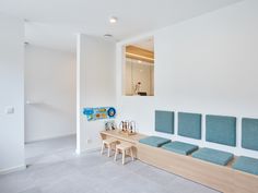 an empty waiting room with blue seats and wooden table in the center, next to a white wall