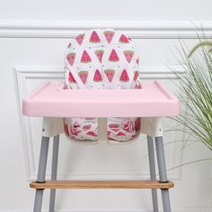 a pink high chair with watermelon print on the seat cover and matching tray