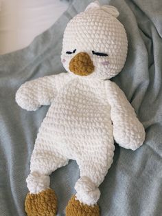 a crocheted white stuffed animal laying on top of a bed