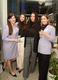 four women in business attire posing for the camera