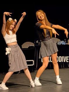 two young women are dancing on stage together