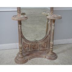 an ornately carved wooden mirror stands against a wall