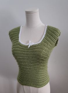 a mannequin wearing a green knitted top with white lace trimmings