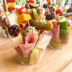 several small cups filled with different types of appetizers on skewered sticks