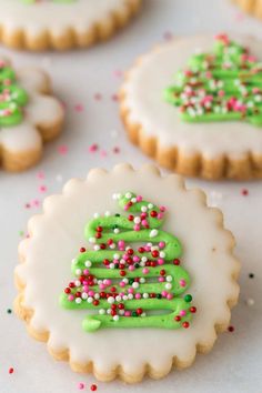 decorated cookies with sprinkles and green frosting on a white tablecloth