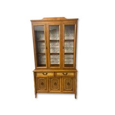 an antique china cabinet with glass doors and drawers