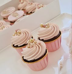 three cupcakes with pink frosting and gold decorations