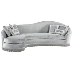 a gray couch with pillows on it and fringe trimming around the armrests