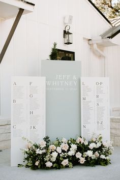 an outdoor ceremony setup with seating cards and flowers on the ground in front of a white building