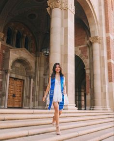 a woman is walking down some steps in front of a building with columns and doors