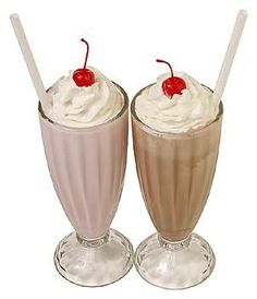 two glasses filled with ice cream and topped with cherries