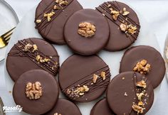 chocolate covered cookies with walnuts and nuts on a white plate next to silverware