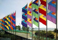 many colorful flags are lined up on the side of the road in front of a fence