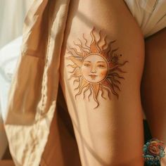 a sun tattoo on the back of a woman's leg, with her eyes closed