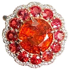 A beautiful 6.31 carat Mandarin Garnet centre stone, surrounded with 2.21 carat round Mandarin Garnet and 0.4 carat White Diamonds, all set in solid 18K Yellow Gold. The Garnet has an amazing luster, with a vivid orange color and is absolutely transparent with no inclusions. The ring is currently sized at US 7, can be resized. We provide free shipping. We accept returns. Feel free to message for more information. Luxury Gia Certified Gemstones, Luxury Round Cut Gemstones With Center Stone, Luxury Round Cut Center Stone Gemstones, Exquisite Round Brilliant Cut Gemstones, Exquisite Round Gemstones With Halo Setting, Red Multi-stone Sapphire Ring, Luxury Red Sapphire Ring, Luxury Cubic Zirconia Gemstones, Exquisite Gia Certified Round Gemstones