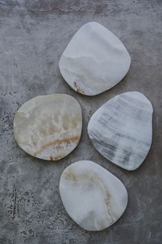 three pieces of marble sitting on top of a cement floor