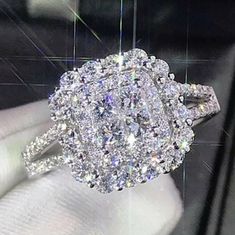 a diamond ring is being held up by someone's hand in front of a display case