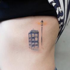 a woman with a tattoo on her stomach has a phone booth and street light in the background