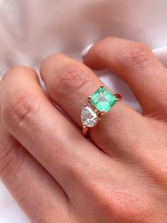 a woman's hand with an emerald and diamond ring