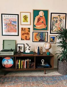 a living room filled with lots of art on the wall above a bookshelf