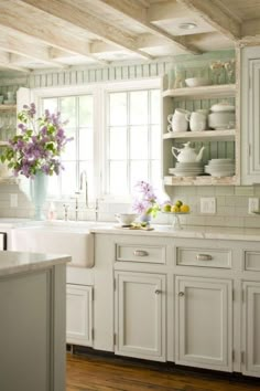 a kitchen filled with lots of white cupboards and counter top next to a window