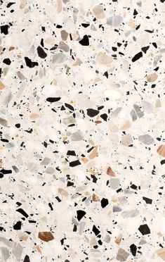 a white and black speckled surface with lots of different colored rocks on the ground