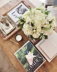 a table topped with books and flowers on top of a wooden table next to a candle