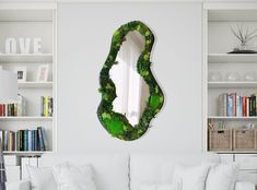 a mirror that is on the wall above a white couch in a room with bookshelves