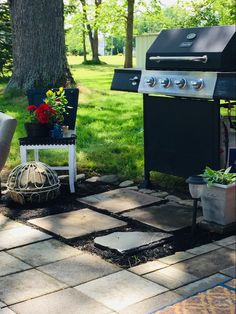 an outdoor patio with grill, chairs and potted plants