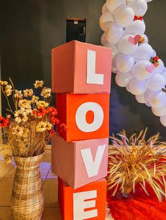 balloons and flowers are on display in front of a love sign