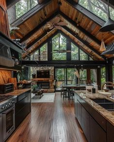 an open kitchen and dining area with wood flooring in a cabin style home on the edge of a forest