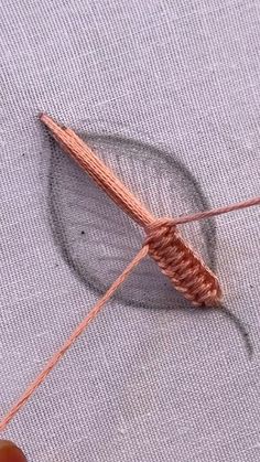 the needle is being used to make an ornament for threading on fabric