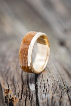 a wooden ring sitting on top of a piece of wood with white gold inlays