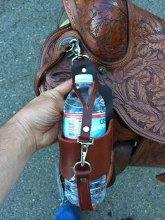 a person is holding a bottle in front of a saddle