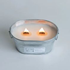 two white candles in a metal container