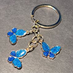 a blue butterfly keychain with glitter on it sitting on a gray counter top