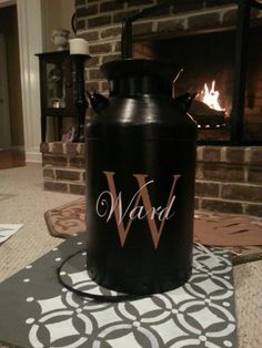 a large black canister sitting on top of a rug in front of a fire place