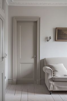 a living room with a white couch and door leading to another room in the background