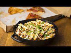 a pan filled with food sitting on top of a wooden table next to slices of pizza