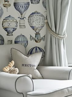 a white couch sitting next to a window covered in blue and white wall coverings