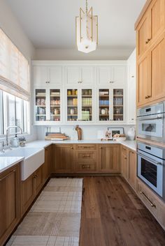 a large kitchen with wooden cabinets and white counter tops, along with an area rug on the floor