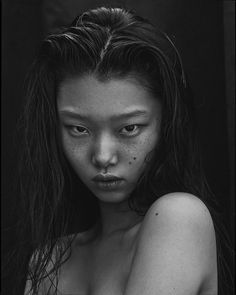 a black and white photo of a woman with freckles on her body, looking at the camera