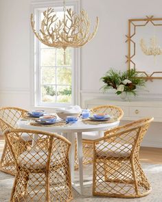 a dining room table with chairs and plates on it, in front of a window