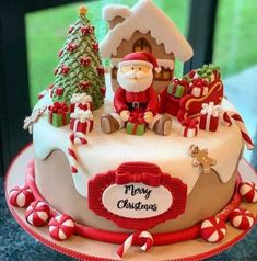 a decorated christmas cake with santa clause and candy canes on the bottom, in front of a window