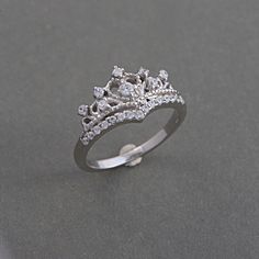 a white gold ring with diamonds on the top and bottom, sitting on a gray surface