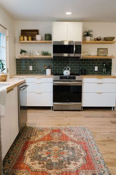 a kitchen with white cabinets and an area rug on the floor in front of it