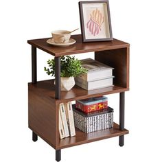 a wooden shelf with books and pictures on it, next to a plant in a vase