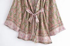 The Selina Floral Kimono Robe wraps you in the elegance of vintage-inspired florals on a muted green canvas, perfect for bringing a touch of nature's calm to your daily routine. Its generous cut and tied waist create an effortlessly flattering shape, ideal for those moments of relaxation or as a sophisticated layer to elevate a simple outfit. This kimono robe is your sanctuary of style, where comfort meets the timeless beauty of floral design. Specs: Material: Cotton, Rayon Bohemian Spring Kimono With Tie Waist, Elegant Green Floral Print Kimono, Elegant Green Kimono With Floral Print, Elegant Spring Cotton Kimono, Green Wrap Kimono With Tie Waist, Casual Spring Kimono With Tie Waist, Green Floral Print Summer Kimono, Chic Green Spring Kimono, Chic Green Kimono For Spring